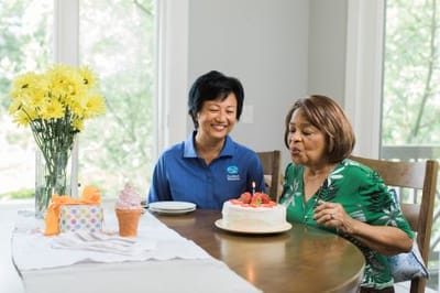 Resident celebrating with cake and staff member