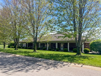 Exterior view of Heritage Assisted Living facility surrounded by trees.