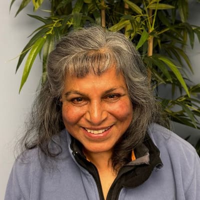 Senior woman smiling with greenery in the background