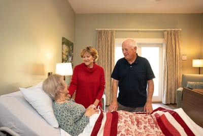 A couple visiting a resident in a cozy room