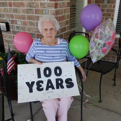 A resident celebrating their 100th birthday with balloons