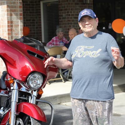 Resident posing with a motorcycle outside the facility