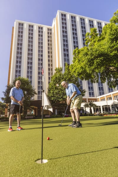 Residents playing golf on the lawn in front of the building