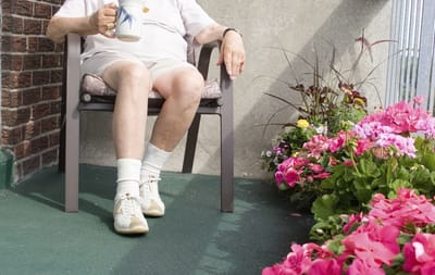 Resident enjoying time on a balcony surrounded by flowers