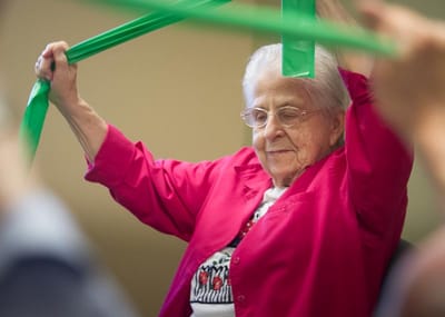 An elderly woman participating in a stretching exercise activity