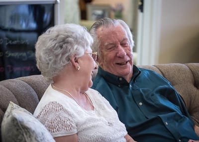 Elderly couple laughing together on a sofa