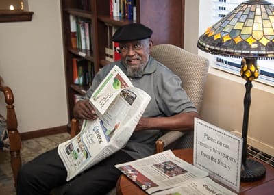 Resident reading a newspaper in a cozy corner