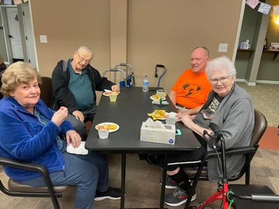 Residents enjoying snacks around a table in a common area