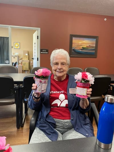 Senior resident proudly displaying potted flowers
