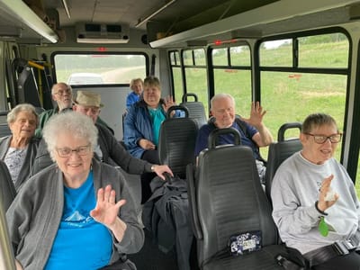 Residents enjoying a bus ride, waving and smiling