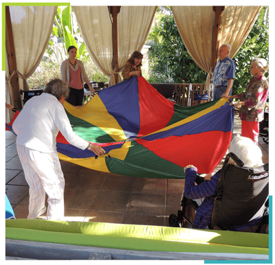 Residents and staff participating in a group activity with a colorful parachute