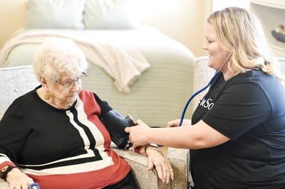 Nurse taking resident's blood pressure in a cozy room