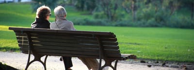 Older couple sitting together on a bench in a park