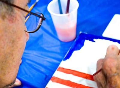 Resident painting at a table during an activity