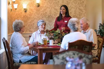 Residents enjoying a meal with staff in a dining area