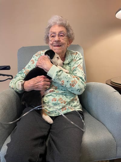 Resident sitting with a puppy in a cozy armchair