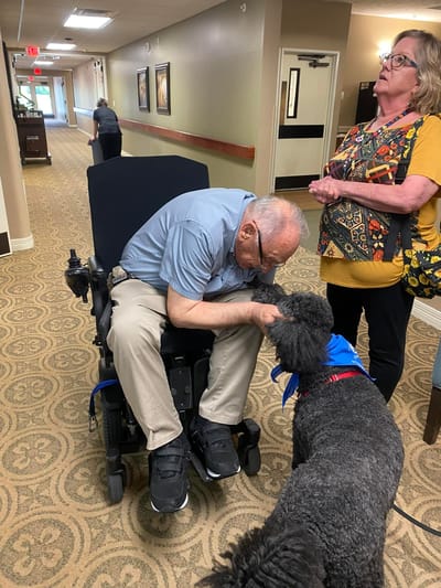 Resident interacting with a therapy dog in the hallway