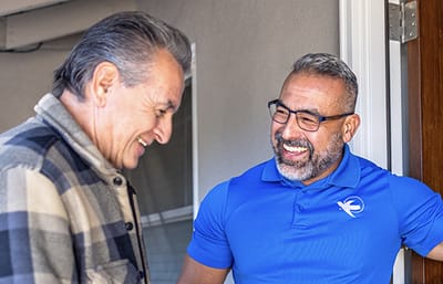 Two men smiling and engaging at the doorway