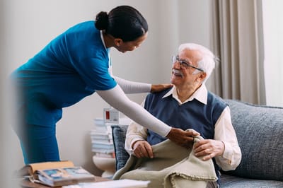 A caregiver assisting a senior resident in a cozy room