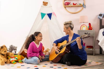 An activity room with a resident and staff member playing guitar