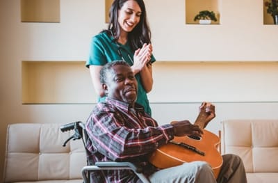 Resident playing guitar with staff member applauding