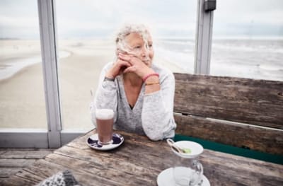 Senior woman enjoying coffee by the beach