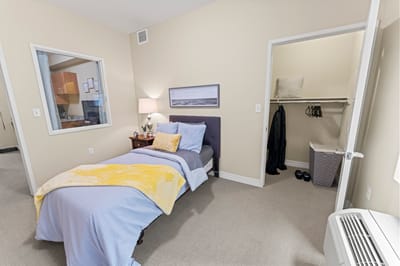 Bright private resident room with bed and closet.