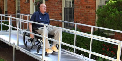 A resident in a wheelchair using an outdoor ramp