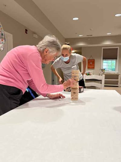 Resident playing Jenga with staff in an activity room