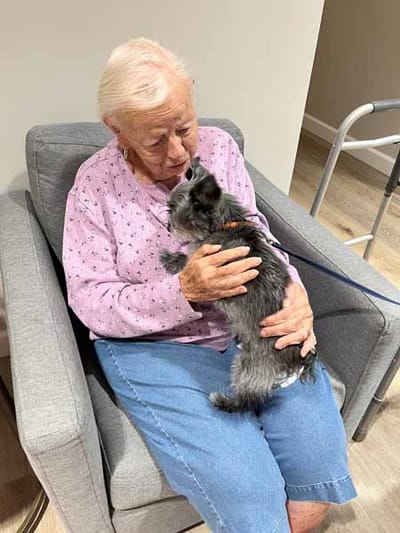 Senior resident cuddling a small dog in a cozy setting
