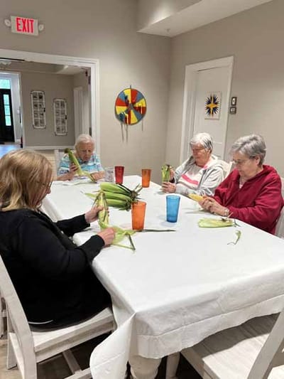 Residents engaged in a corn husking activity at a table