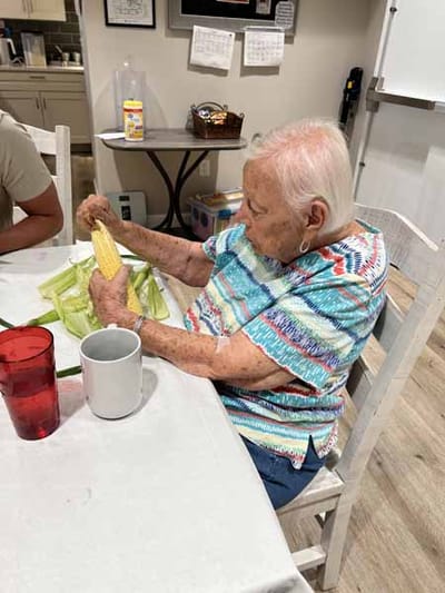 A resident peeling corn at a dining table