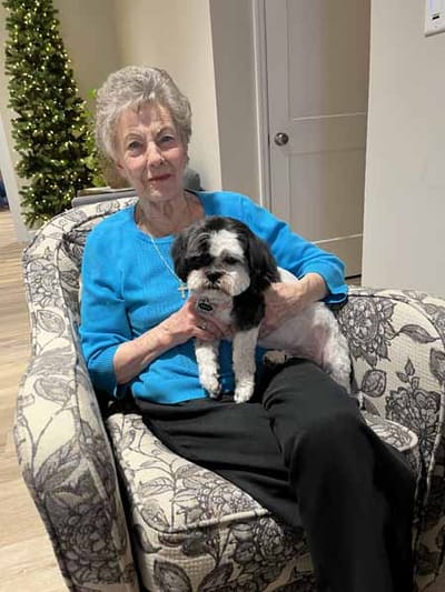 Resident holding a small dog in a cozy chair