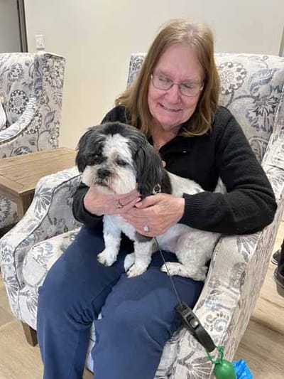 Resident holding a small dog in a cozy seating area
