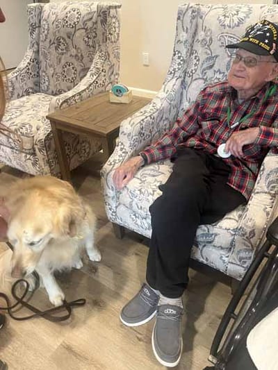 Resident interacting with a therapy dog in a cozy common area