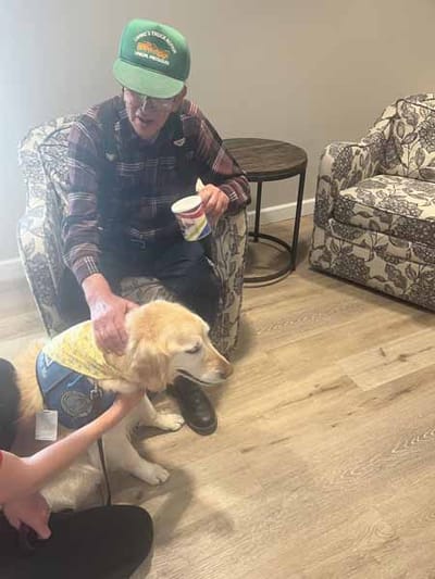 Resident interacting with a therapy dog in a lounge