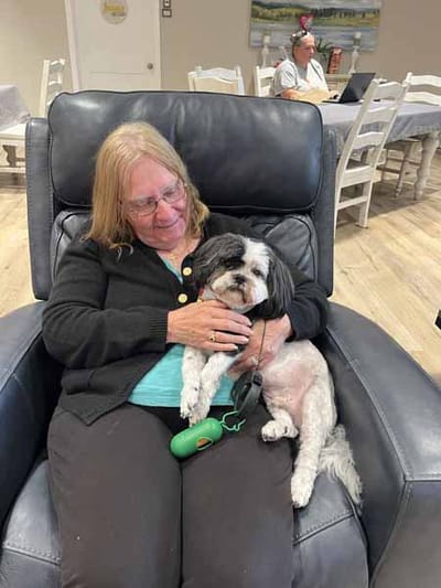 Resident enjoying time with a pet dog in a cozy seating area