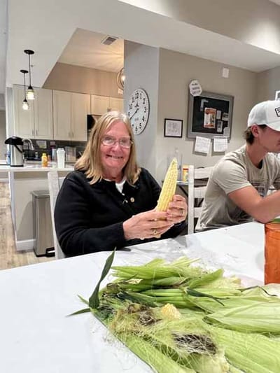 Resident smiling while holding corn indoors