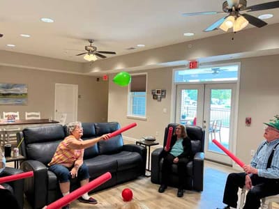 Residents engaged in a fun indoor activity with pool noodles