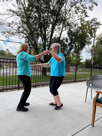 Two seniors dancing on a sunny outdoor patio