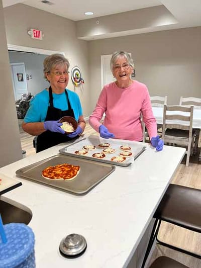 Two residents making personal pizzas in a kitchen
