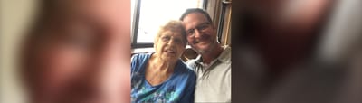 A senior resident and staff member smiling together