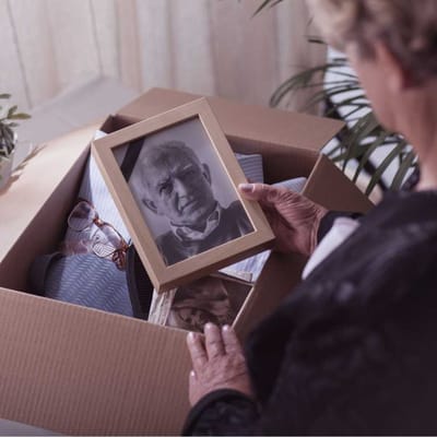 A woman holding a framed photo in a box.