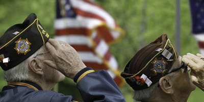 Veterans saluting flags at a commemorative event.