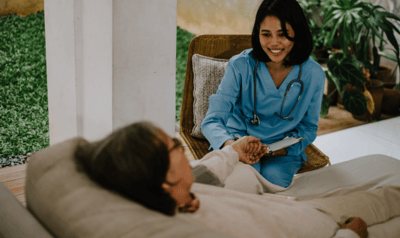 A healthcare worker interacting with an elderly resident outdoors.