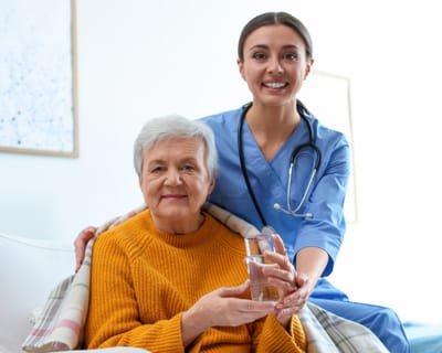 Nurse assisting an elderly resident with a glass of water.