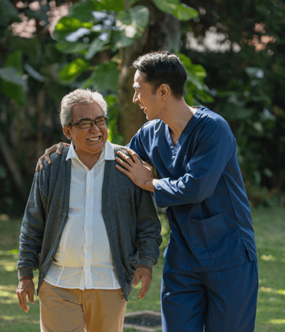 Staff member enjoying laughter with resident outdoors.