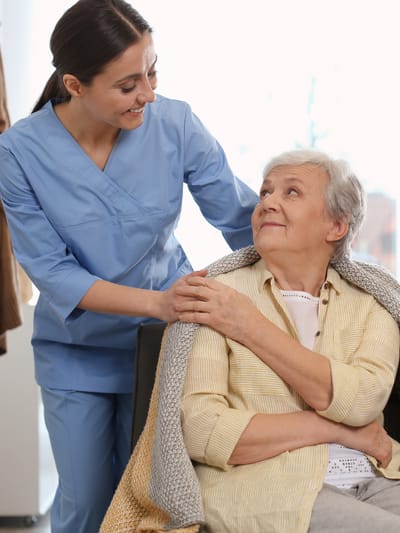 A caregiver interacting with an elderly resident indoors.