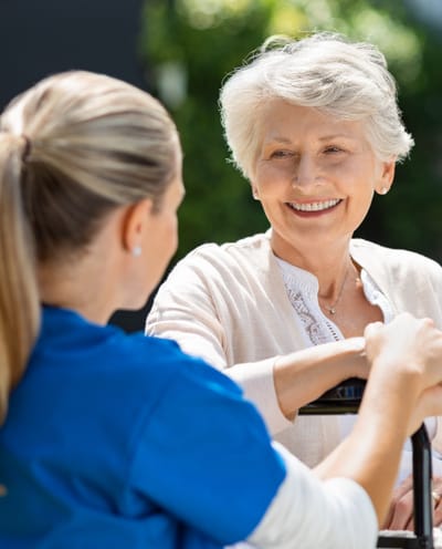 Caregiver interacting with smiling elderly woman