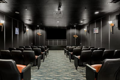 Interior view of a theater room with black seating and projector screen